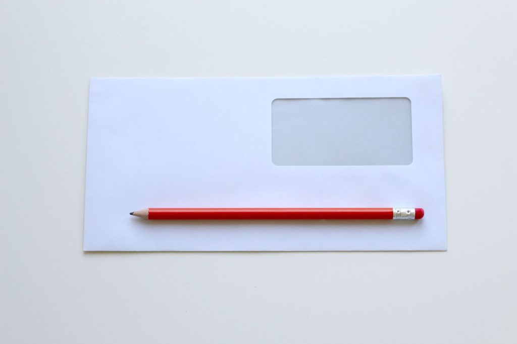 red pencil on top of white window envelope